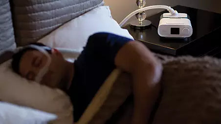 Patient using the Philips Respironics DreamStation Auto CPAP in bed which is equipped with acclimation algorithms such as EZ-Start and SmartRamp