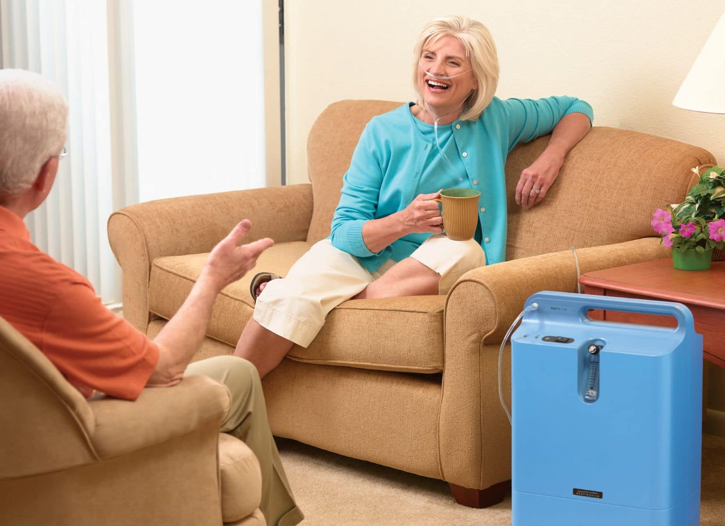Patient using Philips Respironics EverFlo Oxygen Concentrator at home in their living room while having coffee with a guest